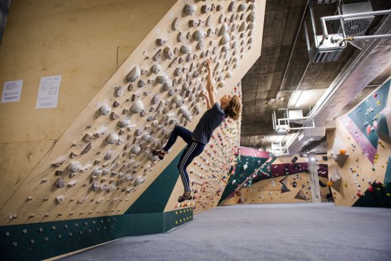 Frau klettert an einer Kletterwand im Basement Boulderstudio