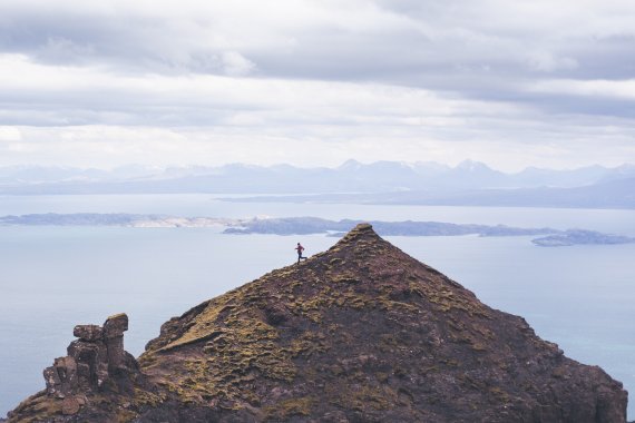 Un corredor de trail corre por una cresta en un paisaje costero escarpado.