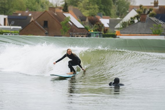 Eine Surferin reitet auf einer künstlichen Welle.