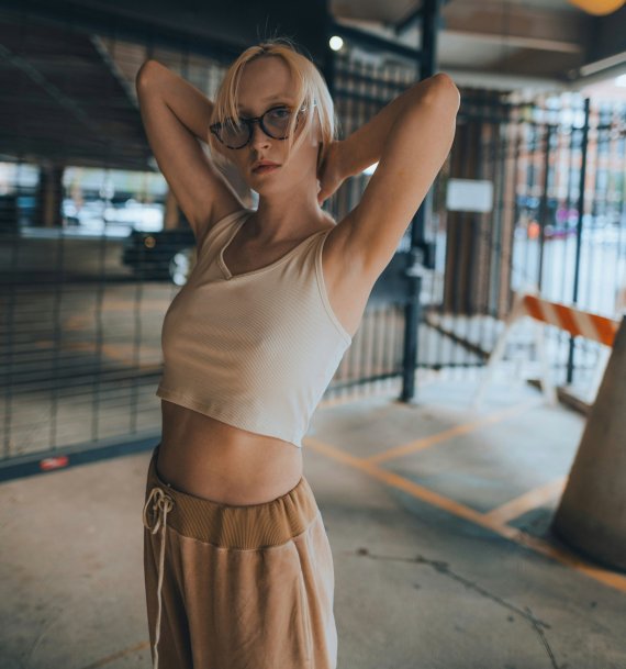 Young woman in athleisure clothes standing in a moody urbanparking garage