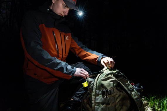 Mann mit Lampe an der Cap schaut in seinen Rucksack