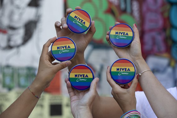 Hände mit untescherschiedlichen Hautfarben halten Nivea Dosen mit Regenbigenflaggen in die Luft