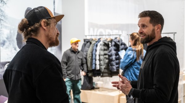 Two men in a sales talk, winter jackets can be seen in the background.