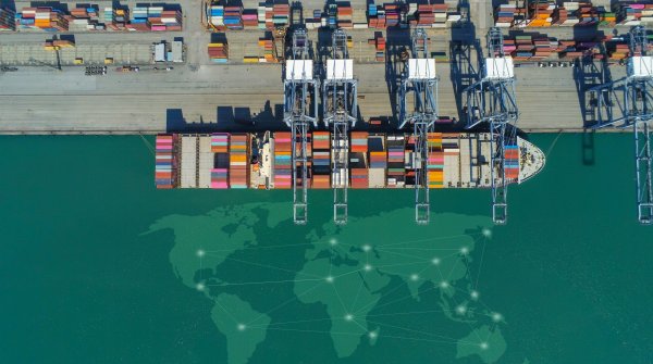 A cargo ship from above. Below it is a map of the world, visualizing supply chains