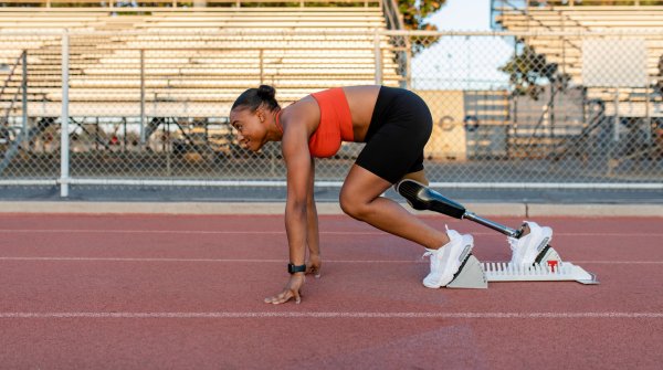 Athletic woman with a prosthetic leg at the start on a running track