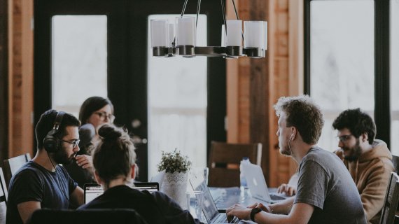 Menschen sitzen am Tisch und arbeiten